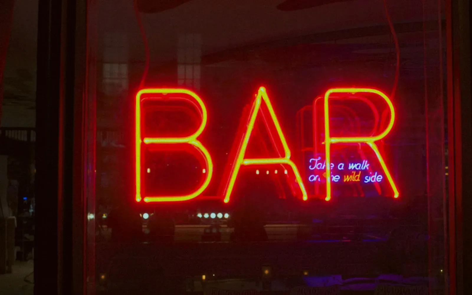 Rot leuchtendes Neonschild „Bar“ in einem dunklen Fenster – Swinger Treff in Deutschland