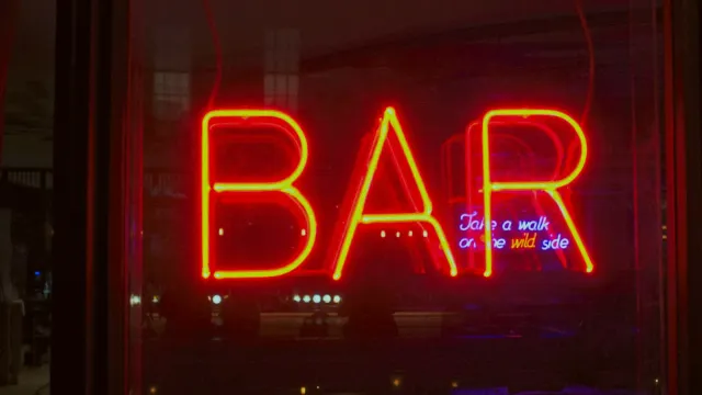 Rot leuchtendes Neonschild „Bar“ in einem dunklen Fenster – Swinger Treff in Deutschland