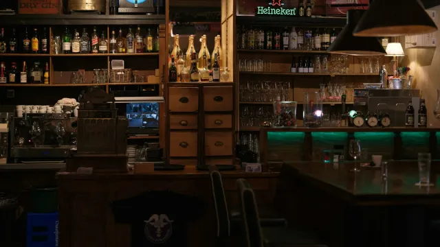 Gedimmte Bar mit Flaschenregalen und grünem Licht – Swingerclub zum ersten Mal als Paar